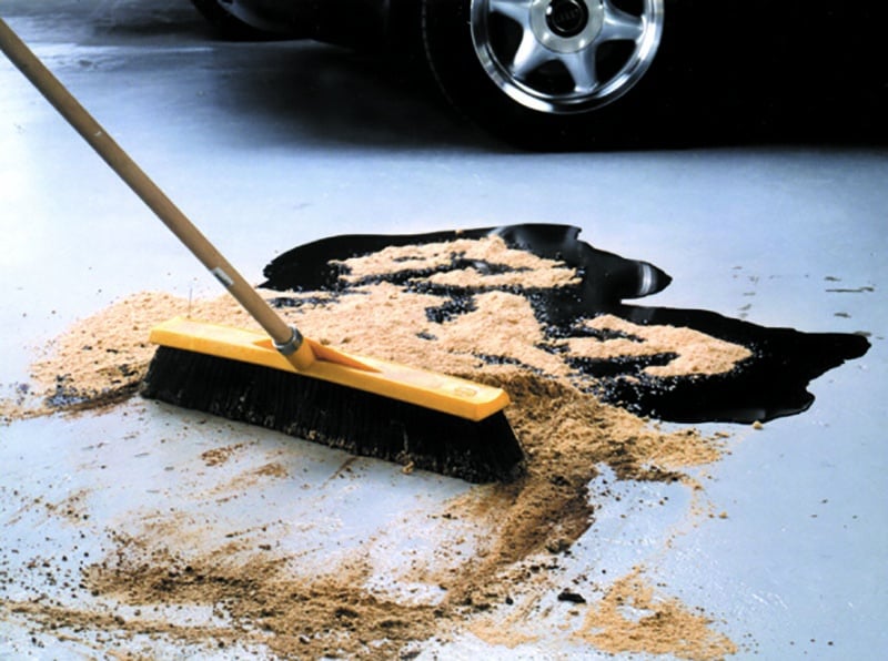 cleaning up an oil spill on a concrete workshop floor using a broom and floor sweep cleaning up an oil spill on a concrete workshop floor using a broom and floor sweep